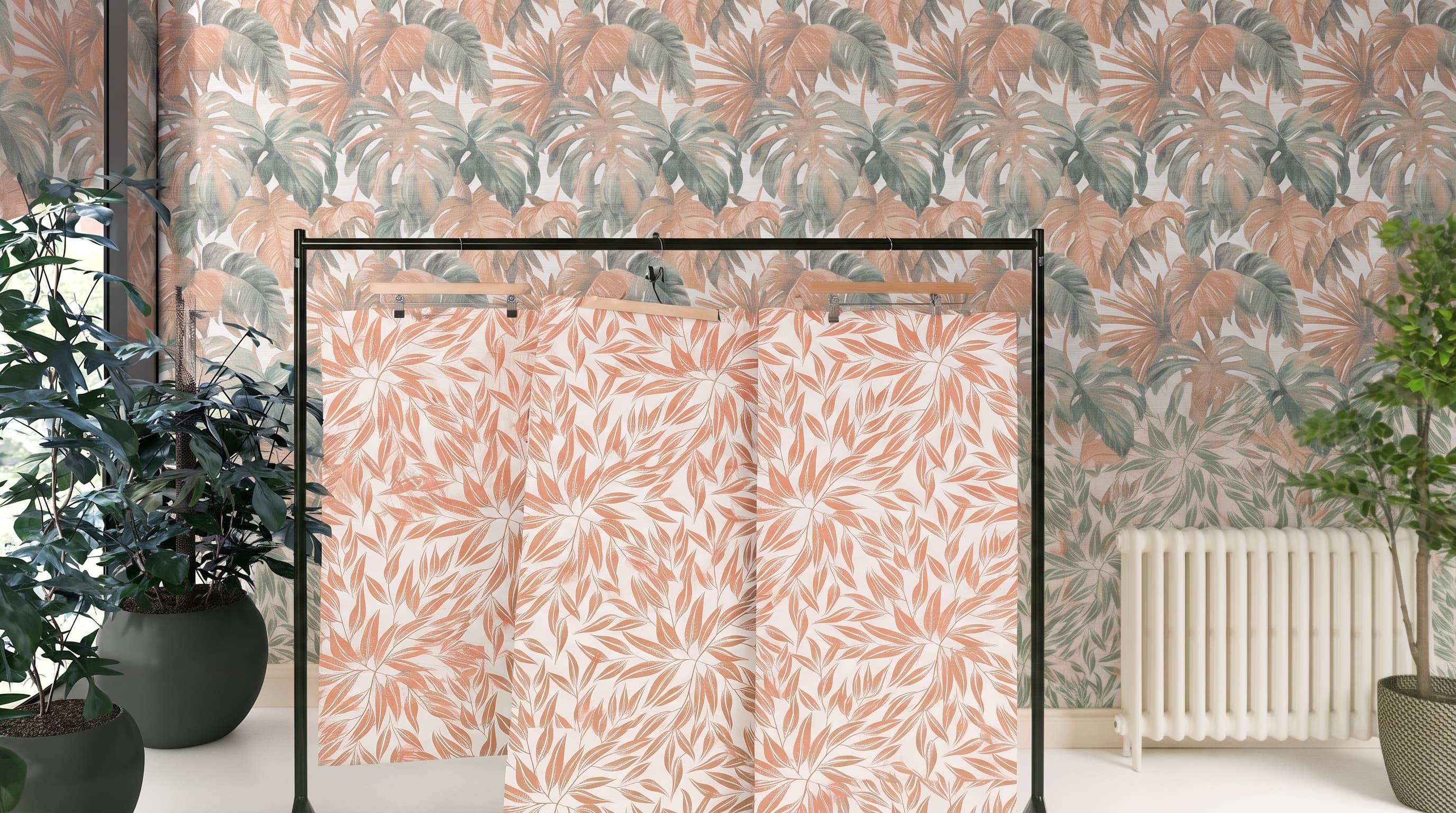 Strips of leaf-print wallpaper hanging on a rail in front of a papered wall
